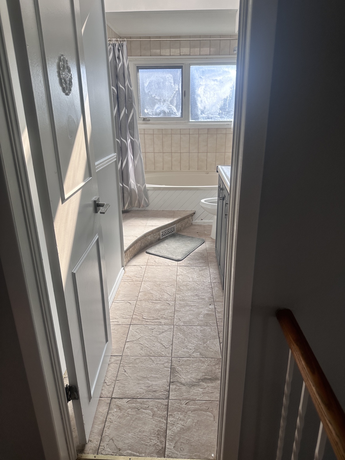 Bathroom before renovation with older tub and floor tile